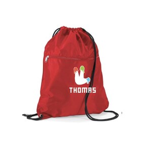 Peut inclure: Un sac &agrave; cordon rouge avec une fermeture &agrave; cordon noire et une poche zipp&eacute;e. Le sac pr&eacute;sente un motif blanc de gouttes de peinture vertes, jaunes et bleues, avec le nom "THOMAS" imprim&eacute; en dessous en lettres blanches.