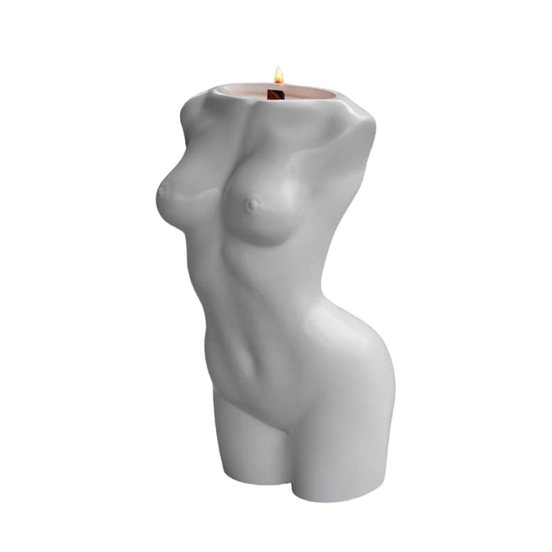 May include: A white candle shaped like a human torso with a lit wick on top.
