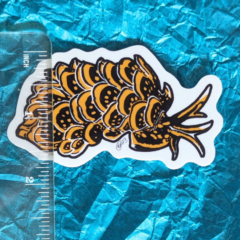 May include: A black and yellow sticker of a sea slug with a textured, segmented body. The sticker is on a blue background.