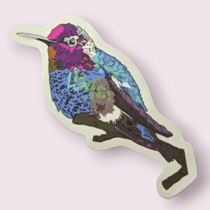 May include: A colorful hummingbird sticker with a blue, green, purple, and white design. The hummingbird is perched on a branch with its wings spread out.