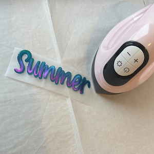 May include: A pink heat press with a black control panel and a clear sheet with the word "Summer" in a blue and purple gradient.