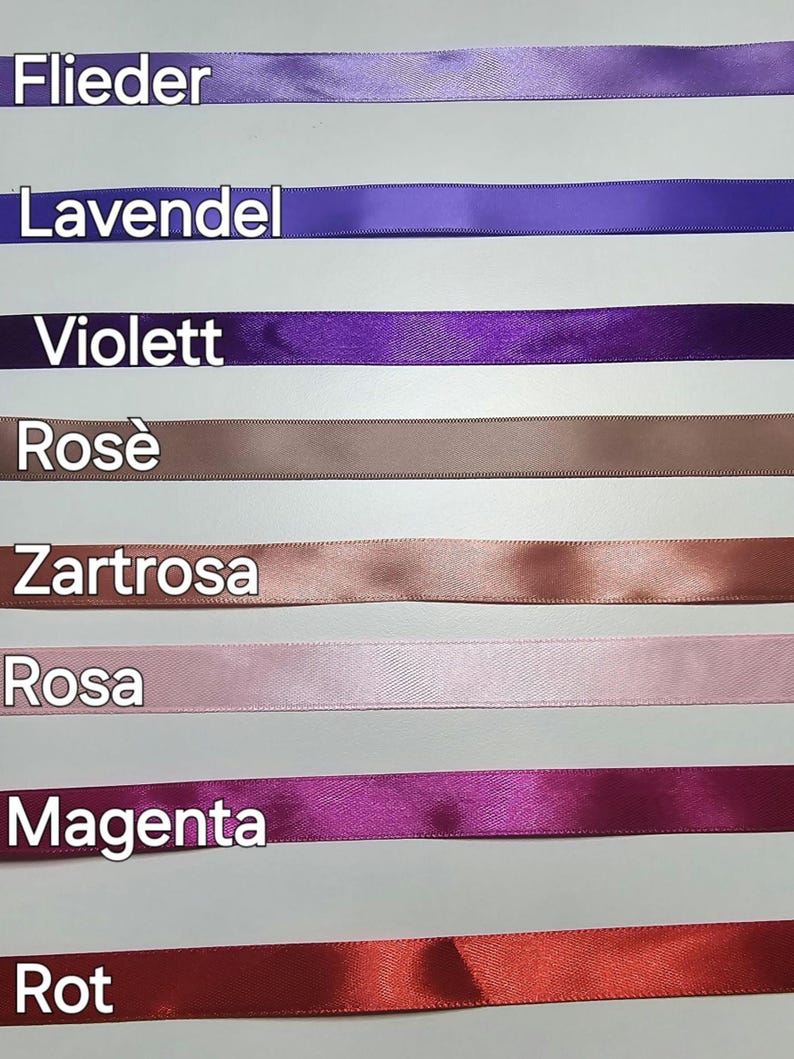Pu&ograve; includere: Una collezione di nastri di raso in vari colori, tra cui lavanda, viola, rosa e magenta. Ogni nastro &egrave; etichettato con il suo nome di colore in tedesco. I nastri sono disposti orizzontalmente su uno sfondo chiaro.