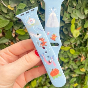 May include: Light blue watch bands featuring illustrations of a pumpkin carriage, glass slipper, dress, and mice. The bands have a whimsical design with a fairytale theme, perfect for adding a touch of fantasy to your wrist.