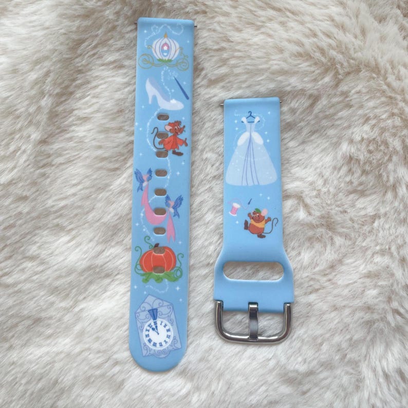 May include: Two light blue watch bands with a Cinderella theme. One band features a carriage, glass slipper, mice, pumpkin, and clock. The other band has a dress and a mouse. Both bands have a silver buckle.