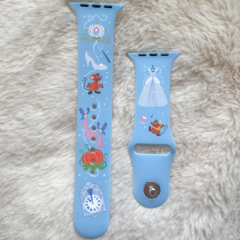 May include: Light blue watch bands featuring a fairytale theme. One band displays a carriage, glass slipper, and pumpkin. The other band shows a ball gown and a mouse. The bands are made of a flexible material.