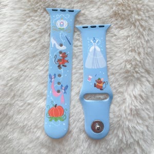May include: Two light blue watch bands with a fairytale theme. One band features a pumpkin, carriage, glass slipper, and mice. The other band has a dress, spool of thread, and a mouse. The bands are made of a flexible material.