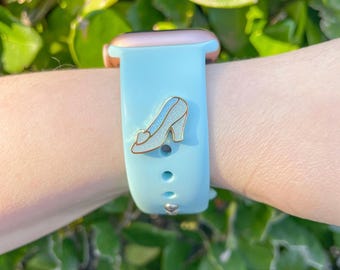 May include: A light blue silicone Apple Watch band with a gold metal buckle and a glass slipper charm.