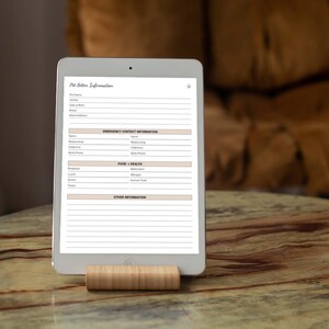 May include: A white tablet with a blank pet sitter information form. The form includes sections for pet name, breed, date of birth, emergency contact information, food and health, and other information.