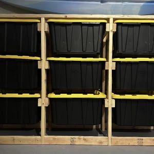 May include: A wooden storage shelf with nine black storage bins with yellow lids. The shelf is made of unfinished wood and has a rustic look.