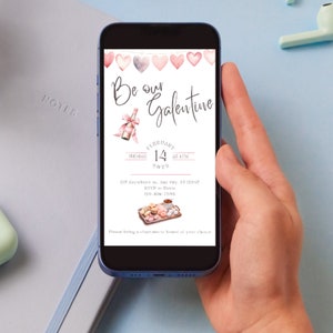 May include: A pink and white digital invitation on a smartphone screen. The invitation reads "Be our Galentine" with a pink heart garland, a bottle of champagne, and a plate of donuts. The date is February 14th at 4 PM.