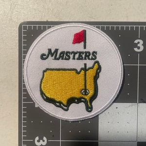 May include: White embroidered patch with a gold outline of the United States, a red flag, and the text "Masters" in green.