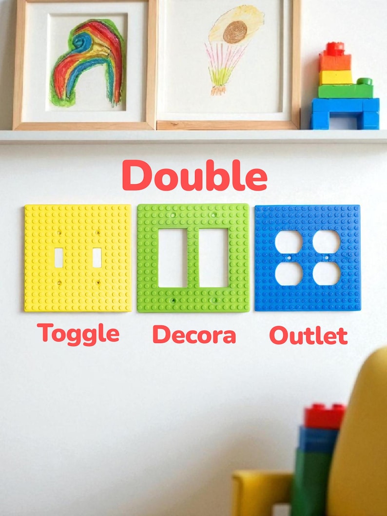 K&ouml;nnte beinhalten: Drei farbenfrohe Wandplatten im Lego-Stil: gelber Schalter, gr&uuml;ner Decora und blaue Steckdose. Das Wort "Double" steht &uuml;ber den Platten, mit den W&ouml;rtern "Toggle", "Decora" und "Outlet" darunter. Kunstwerke und Legosteine befinden sich auf einem Regal dar&uuml;ber.