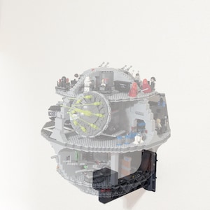 May include: A gray, spherical building block model of a space station featuring multiple interior levels, small character figures, and a large circular laser dish, mounted to a wall using a black, angular, lattice-patterned plastic bracket.