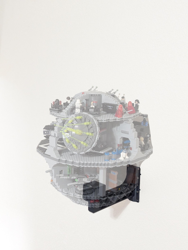 May include: A gray, spherical building block model of a space station featuring multiple interior levels, small character figures, and a large circular laser dish, mounted to a wall using a black, angular, lattice-patterned plastic bracket.