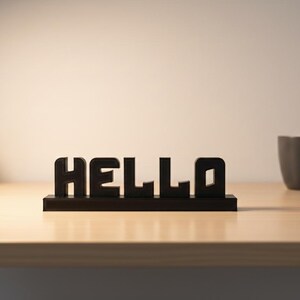 May include: Black wooden "HELLO" sign on a wooden surface. A small potted plant and a grey mug are also on the surface. The sign is a decorative item.
