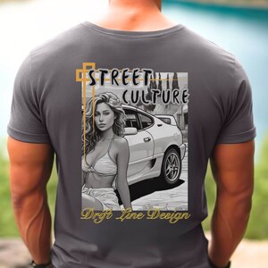 May include: A gray t-shirt with a graphic print of a woman standing next to a white car. The graphic also includes the text "Street Culture" and "Drift Line Design".