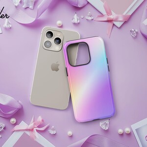 a gold iPhone with a colorful case, surrounded by various accessories such as pearls, ribbons, and flowers on a purple background.