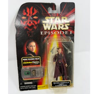 Könnte beinhalten: Star Wars Episode I Queen Amidala Actionfigur mit Blasterpistolen, in Originalverpackung. Die Verpackung zeigt das Gesicht von Darth Maul und den Text "NOW FIGURES TALK!" und "COMMTECH CHIP". Ab 4 Jahren.