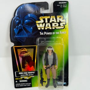 May include: A Star Wars "The Power of the Force" action figure of a Rebel Fleet Trooper. The figure is in its original packaging, with a picture of Darth Vader and the text "REBEL FLEET TROOPER" and "BLASTER PISTOL AND RIFLE".