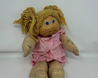 Muñeca Cabbage Patch Kids vintage de 1985, cabello rubio de lana, ojos azules, atuendo rosa, años 80.