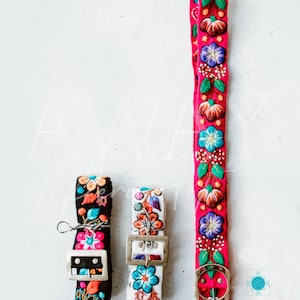 May include: Three embroidered belts with floral patterns. The belts are in black, white, and pink with colorful embroidery. The belts have silver buckles.