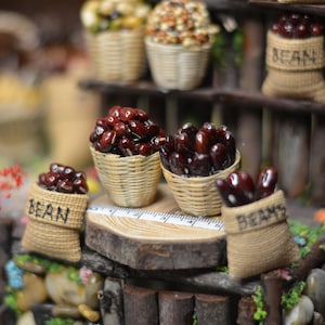 Könnte beinhalten: Eine Miniatur-Ausstellung mit kleinen Körben, gefüllt mit getrockneten Bohnen, beschriftet mit "Bean". Die Körbe sind auf einem Holzregal mit rustikalem, braunem Finish angeordnet.