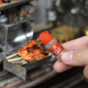 Pode incluir: Um pequeno frasco vermelho e branco de tempero de páprica com o texto "Paprika Üstün Kalite" no rótulo.