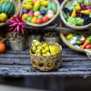 Pode incluir: Uma exposição de comida em miniatura com várias frutas e vegetais, incluindo uma melancia, bananas e um repolho roxo, tudo organizado em pequenas cestas de vime.