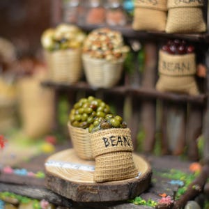 May include: A miniature wooden market stall with various bags of beans, nuts, and other goods. The stall is decorated with rustic wood and has a small wooden sign that reads "BEAN".