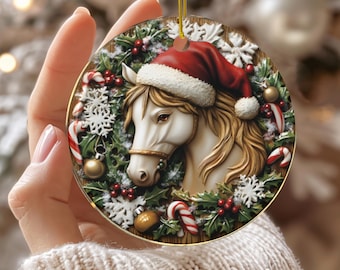 Könnte beinhalten: Runder Weihnachtsbaumschmuck aus Keramik mit einem weißen Pferd mit Weihnachtsmütze. Das Pferd ist von Stechpalmen, Schneeflocken, Zuckerstangen und goldenen Kugeln umgeben. Das Wort "CERAMIC" ist unten aufgedruckt.