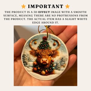 May include: A round Christmas ornament featuring a Highland cow with a festive Christmas tree on its head and a garland of ornaments around its neck. The ornament has a winter scene background and a gold string for hanging.