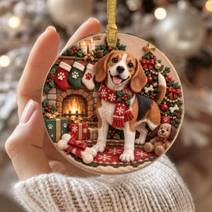 Könnte beinhalten: Ein runder Weihnachtsschmuck mit einem Beagle, der einen roten Schal mit Schneeflocken trägt, vor einem Kamin mit Strümpfen, Geschenken, einem geschmückten Baum und einem kleinen Plüschhund, aufgehängt an einer goldenen Schleife.