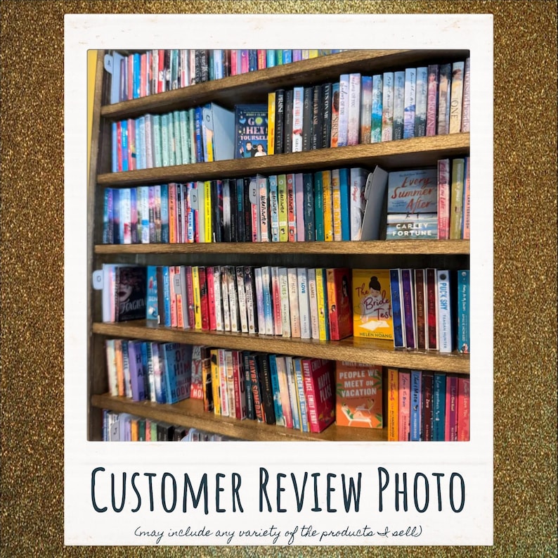 May include: A tall wooden bookshelf filled with numerous books arranged in rows. The spines display a variety of colors, titles, and authors. Some books are positioned with their front covers facing forward, including titles like Go Hex Yourself.