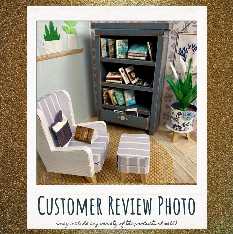 May include: A miniature room scene featuring a blue wooden bookshelf filled with tiny books, a light blue and white striped armchair with a matching ottoman, a small potted plant in a blue and white patterned pot, and a book resting on the chair.