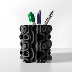 May include: Black wavy desktop organizer with a green marker and two pens.