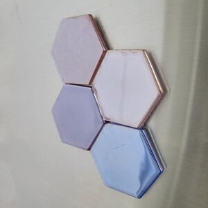 May include: Four hexagonal tiles in shades of purple and blue. The tiles are arranged in a cluster, with the blue tile at the bottom.