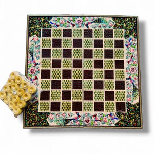 May include: A decorative wooden chess board with a floral and peacock design. The board has a checkerboard pattern with alternating dark red and light green squares. A set of ivory-coloured chess pieces is included.