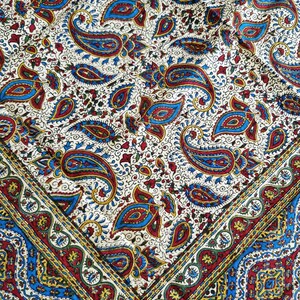 May include: A white fabric with a paisley pattern in shades of blue, red, and gold. The fabric has a border with a repeating pattern of blue, red, and gold.