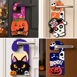 Può includere: Quattro appendiporta decorativi a tema Halloween. Uno mostra una zucca con caramelle, uno un teschio con cappello da pirata e la scritta HALLOWEEN, uno un gatto nero con una luna, e uno una zucca con la scritta BOO e dei piccoli teschi.