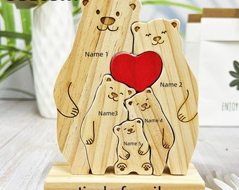 Puede incluir: Corte de madera de una familia de osos con un corazón rojo en el centro. Los osos están dispuestos en formación familiar, con el oso más grande en la parte inferior y el más pequeño en la parte superior. Los osos están etiquetados con nombres: Nombre 1, Nombre 2, Nombre 3, Nombre 4 y Nombre 5. La base del corte está etiquetada como "La familia de Jim".