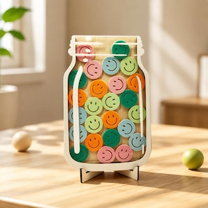 May include: A wooden jar-shaped display stand featuring a clear front panel filled with numerous small, colourful circular tokens. Each token is embossed with a smiling face and comes in shades of pink, orange, green, and blue.