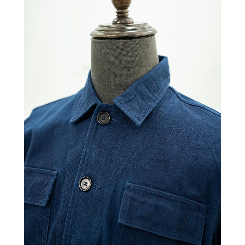 May include: A dark blue denim work jacket with a button-up closure and two large pockets on the front.