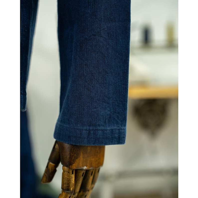 May include: Close-up of the dark blue denim sleeve of a jacket. The sleeve is folded over and the stitching is visible.