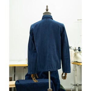 May include: A dark blue denim jacket with a button-up front and long sleeves. The jacket is on a mannequin and is displayed against a white background.
