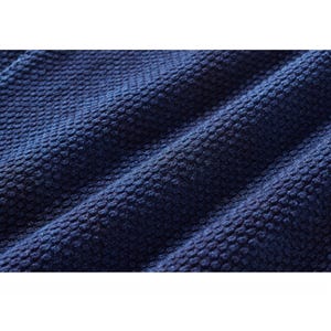 Peut inclure: Gros plan sur un tissu bleu marine texturé. Le matériau présente un motif en relief, ponctué, créant une surface visuellement intéressante. La couleur bleu foncé du tissu est uniforme, avec de subtiles variations de lumière et d'ombre.