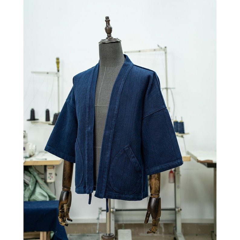 May include: A dark blue denim kimono with a traditional Japanese style. The kimono has a relaxed fit and features a wide collar and long sleeves. The fabric is soft and comfortable, and the kimono is perfect for layering over other clothing.