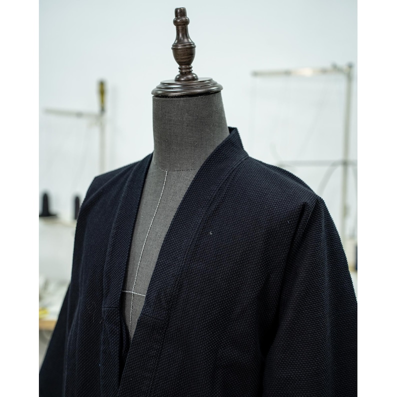 May include: A black, textured, cotton kimono with a V-neck and long sleeves.