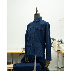 May include: A dark blue denim work shirt with a button-up front, long sleeves, and multiple pockets.