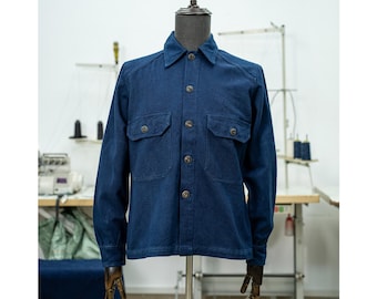 May include: A dark blue long-sleeved shirt with a button-down collar and two large pockets. The shirt is made of a soft, textured fabric.