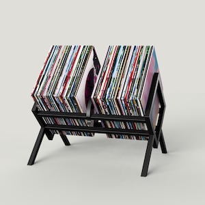May include: Black metal record stand with two rows of vinyl records. The stand has a geometric design and is made of sturdy metal.